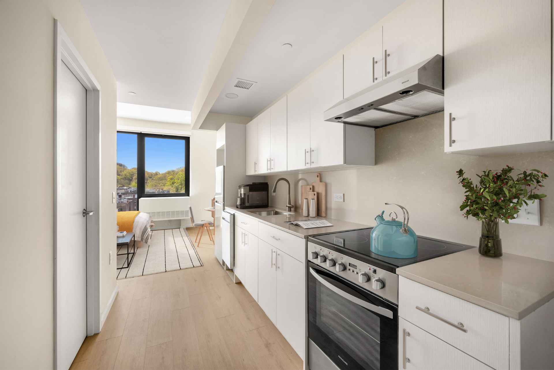 Modern kitchen with white cabinets leading to living room at an apartment at Tryon North, new apartment rentals in Inwood.
