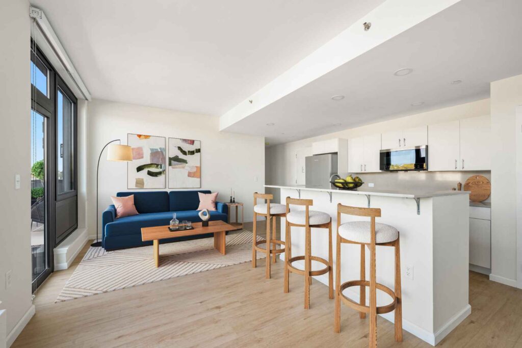 Spacious dining/living room with kitchen island & balcony at Tryon North Inwood apartments near Fort Tryon Park.